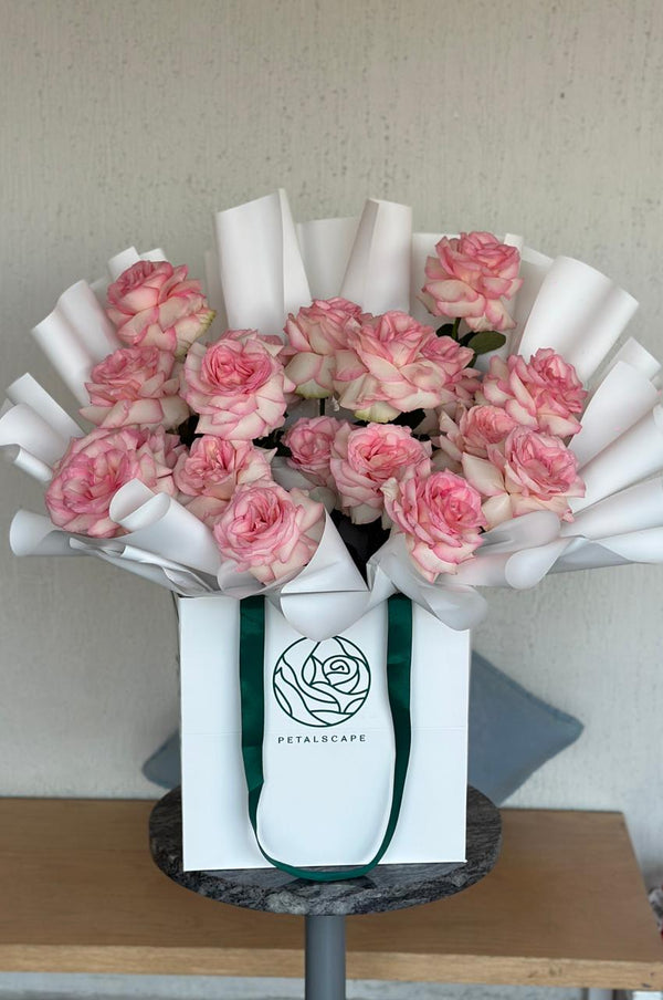 Bouquet of pink flowers in a white box with 'Petalscape logo on a wooden surface.