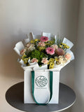 Bouquet of flowers in a white box with a visible brand logo on a neutral background