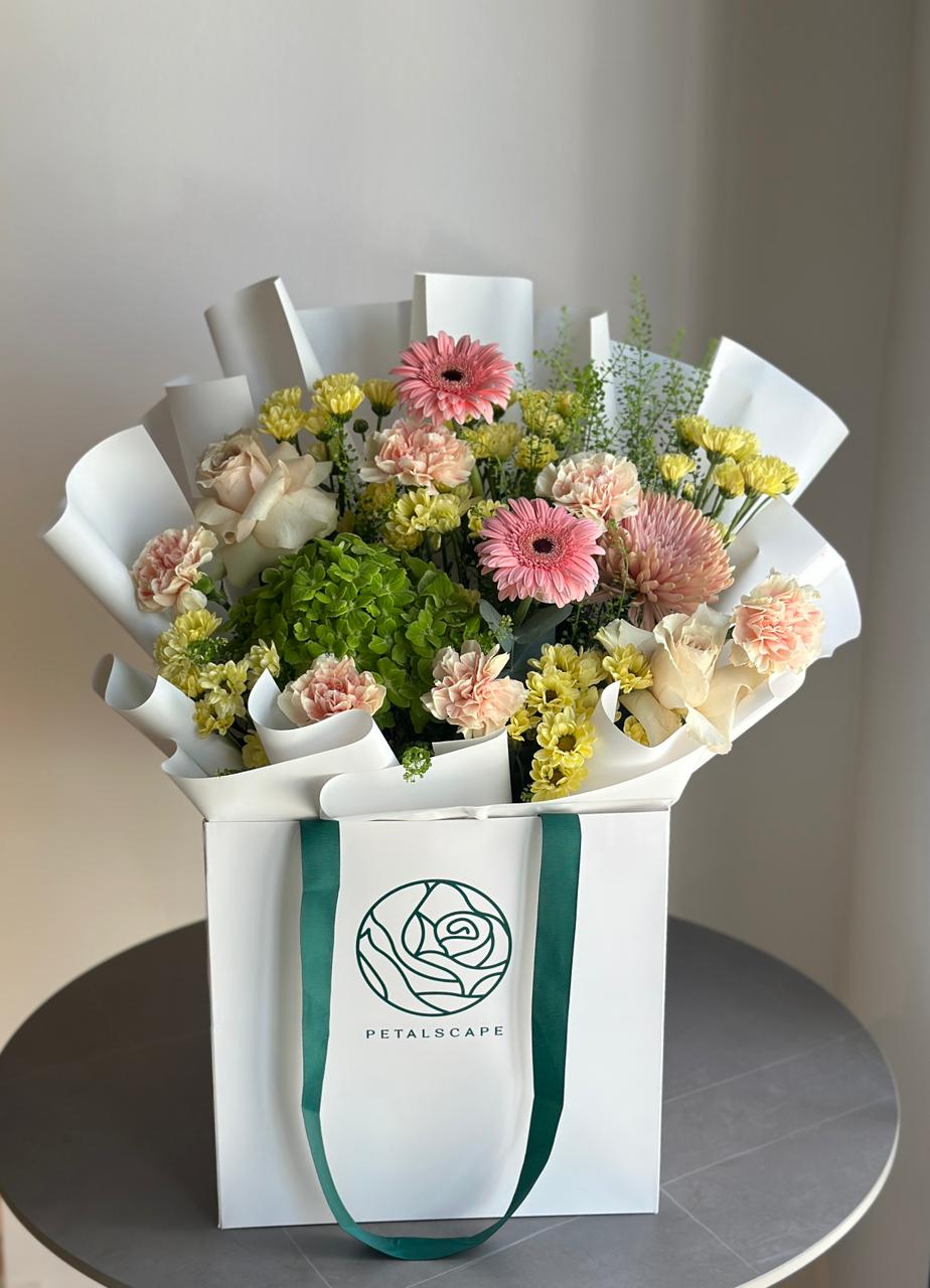 Bouquet of flowers in a white box with a visible brand logo on a neutral background