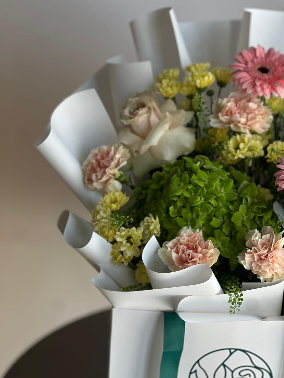 Bouquet of flowers in a white paper basket on a neutral background