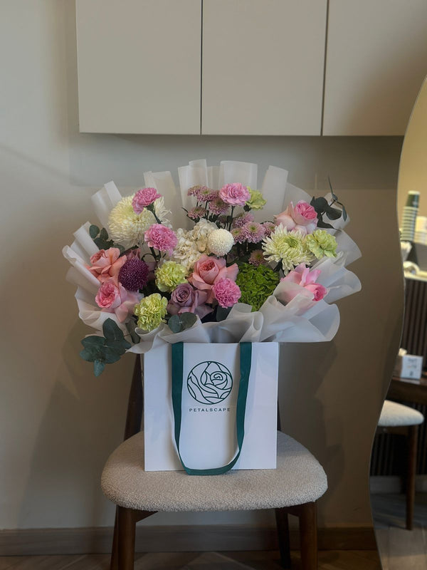 Bouquet of flowers in a white paper wrap on a chair with a visible brand logo.