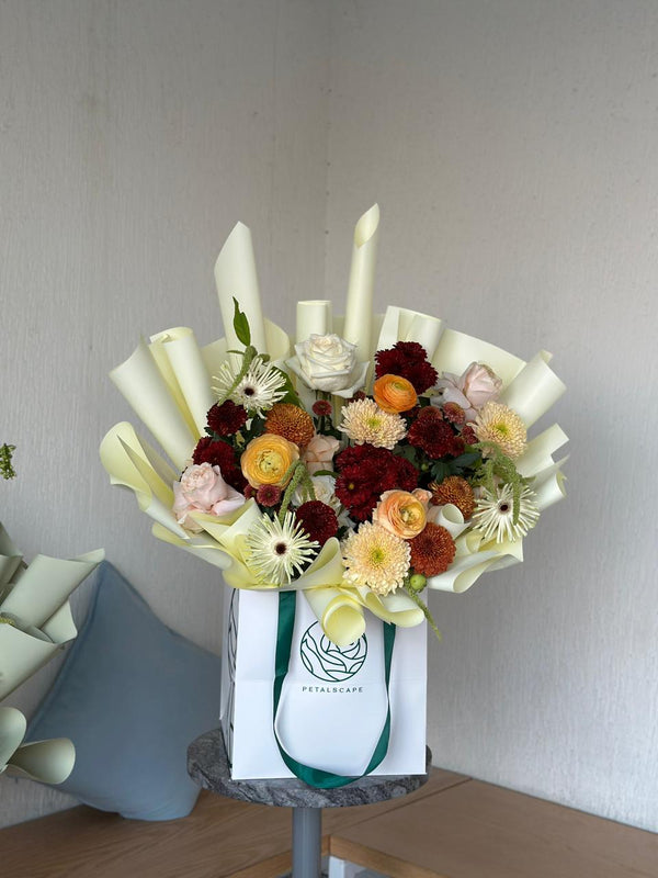 Bouquet of flowers in a white box with a visible brand logo on a neutral background